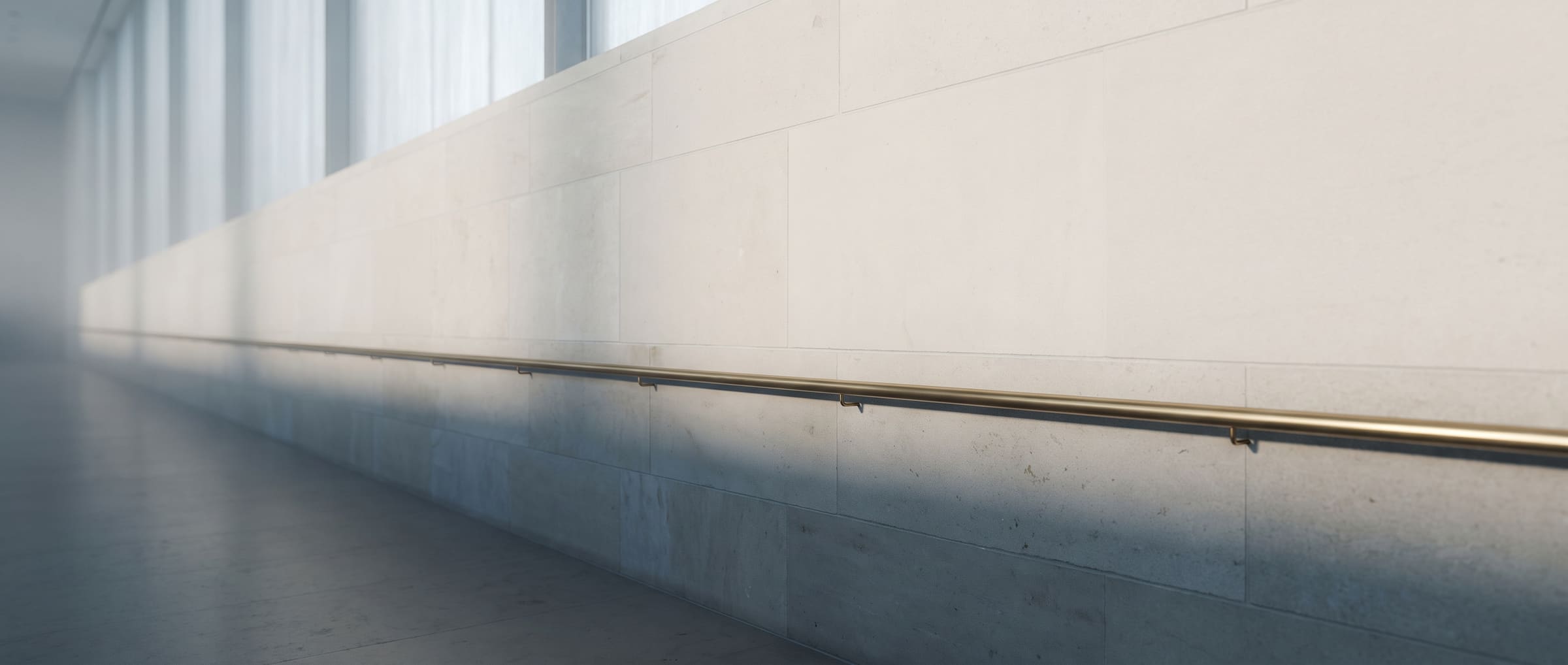 A limestone corridor with a brass handrail in soft morning light